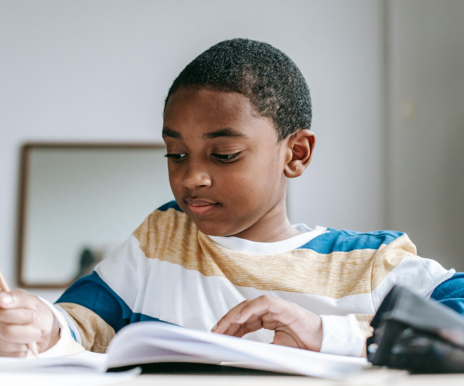 Petit garçon métisse qui écrit sur un cahier