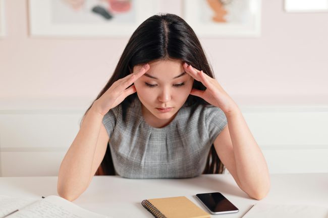 Femme stressée avec son cahier et son téléphone sur la table