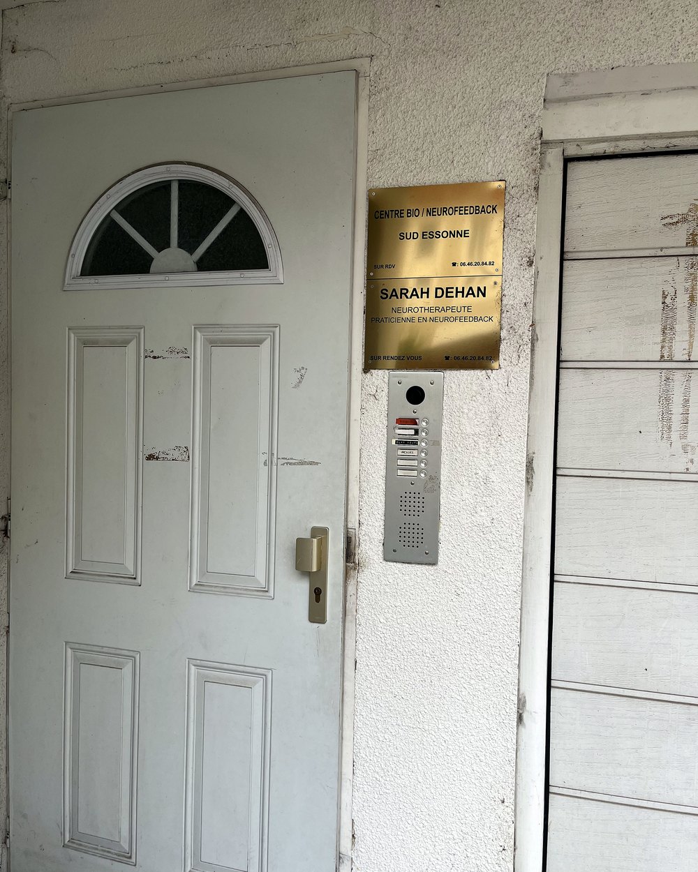 Street-side entrance door, with the centre’s plaque and the intercom